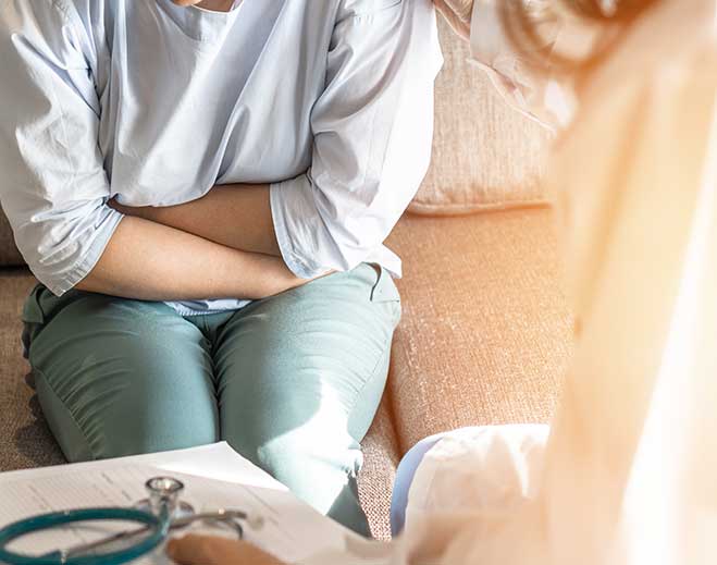 Patient holding abdomen during medical consultation