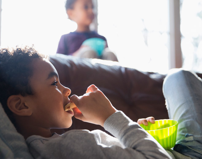 Niño comiendo refrigerio mientras ve televisión