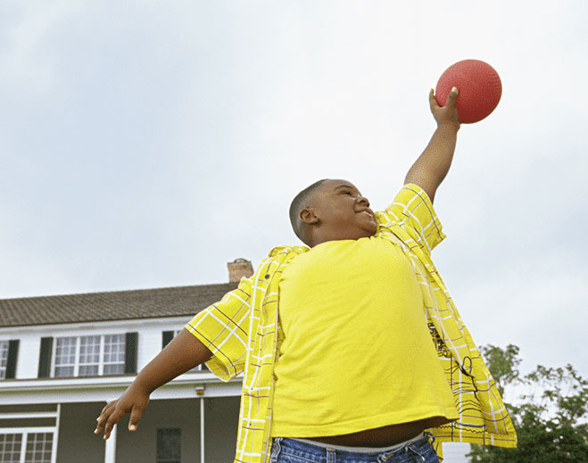 Child reaching upward while holding ball