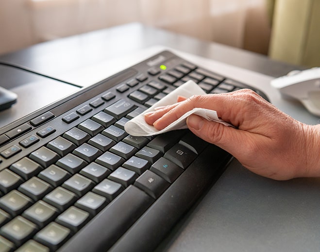 Persona desinfectando teclado de computadora
