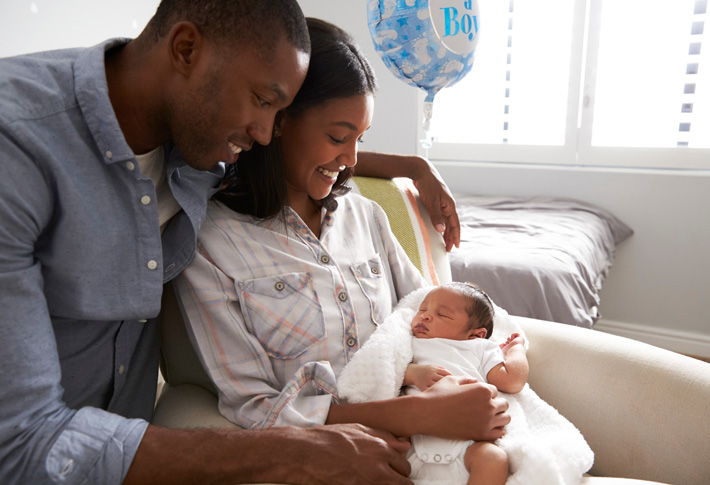 New parents holding newborn with celebration balloon