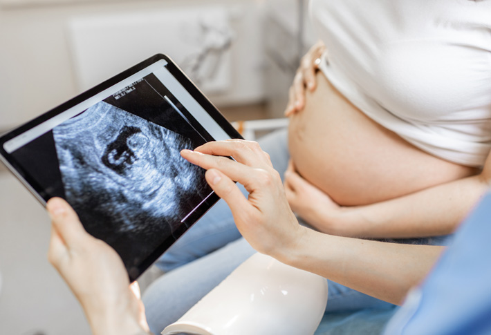 Pregnant person viewing ultrasound scan on tablet
