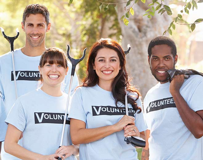 Group of volunteers holding trash pickers outdoors
