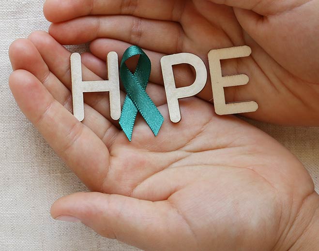 Hands holding “HOPE” with teal awareness ribbon