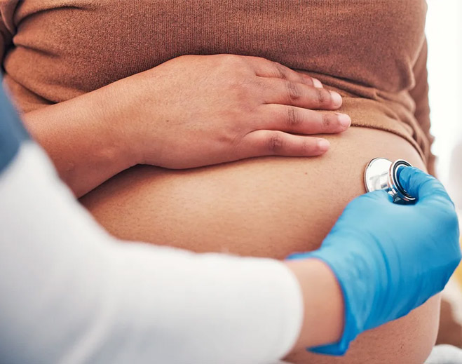 Doctor using stethoscope on pregnant belly