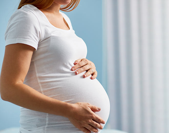 Pregnant person holding belly in profile